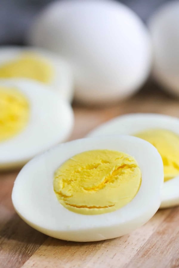 Close-up of sliced hard-boiled eggs on a wooden surface, displaying the yellow yolk and white exterior.