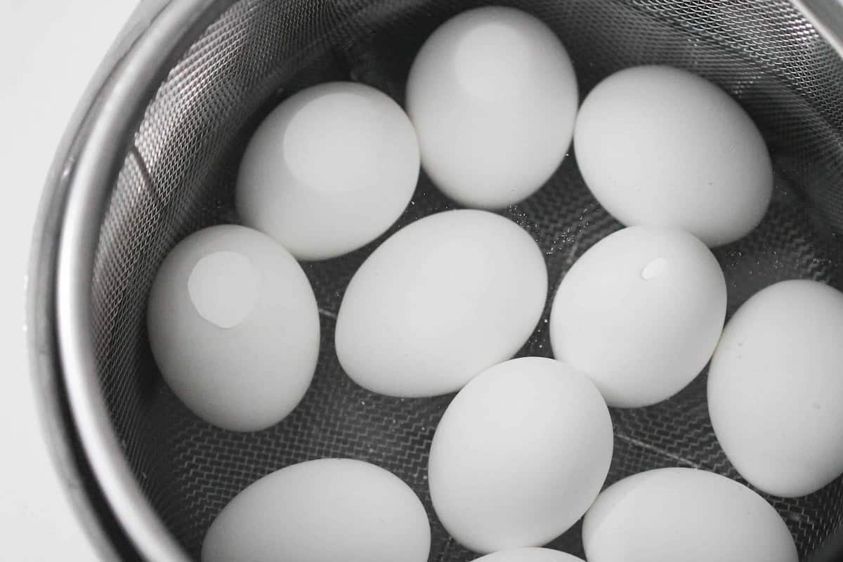 White eggs are placed in a metal colander.