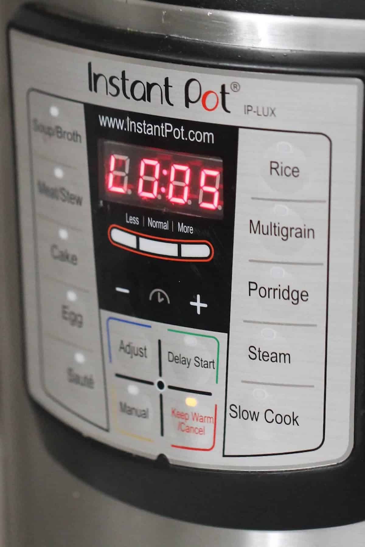 Close-up of an Instant Pot control panel showing buttons for various cooking modes and a digital display reading "0:05.
