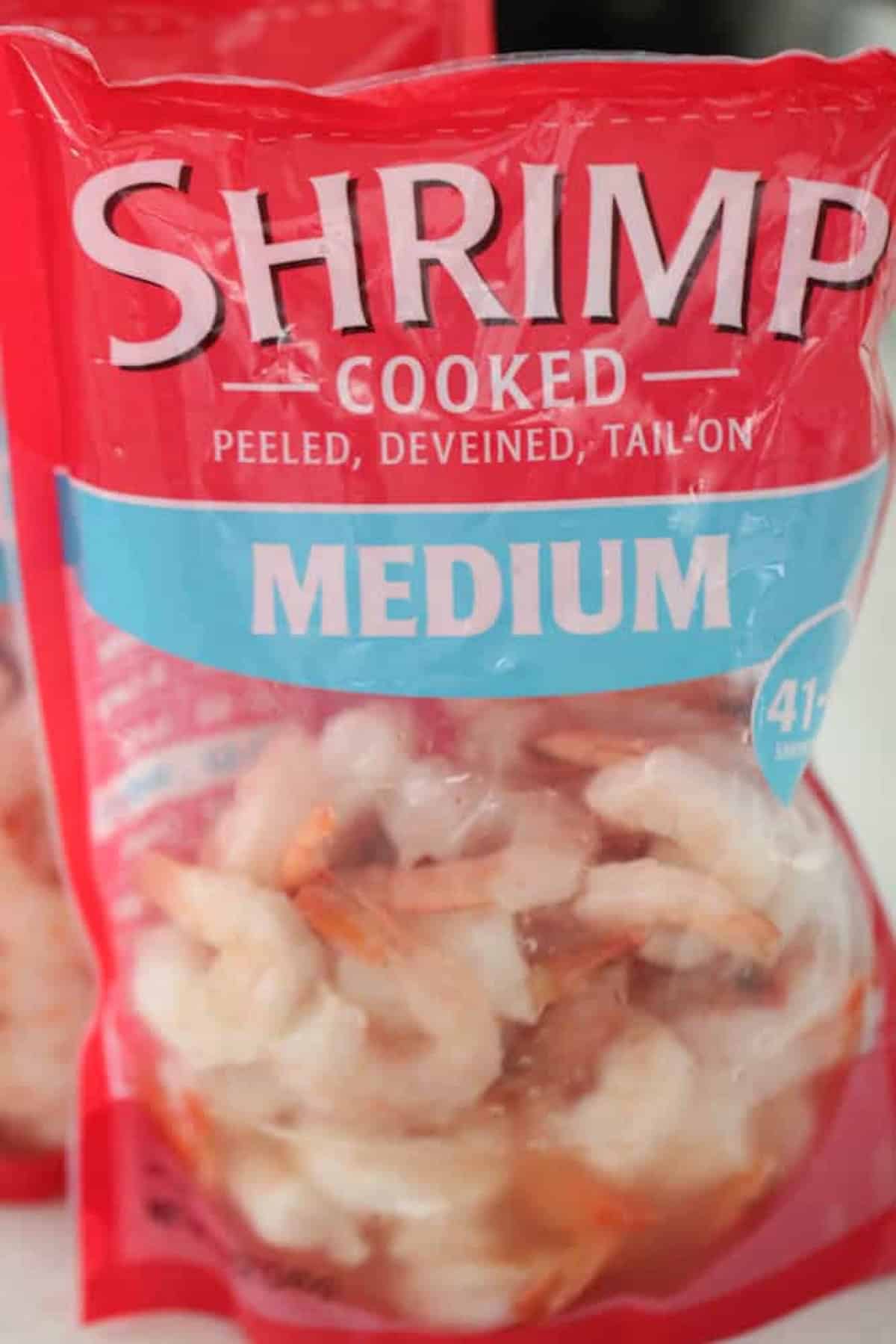 A red and blue bag labeled "Shrimp Cooked, Peeled, Deveined, Tail On, Medium" contains frozen shrimp.