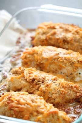 Close-up view of a glass baking dish containing four breaded and baked chicken breasts, with a golden-brown crust.