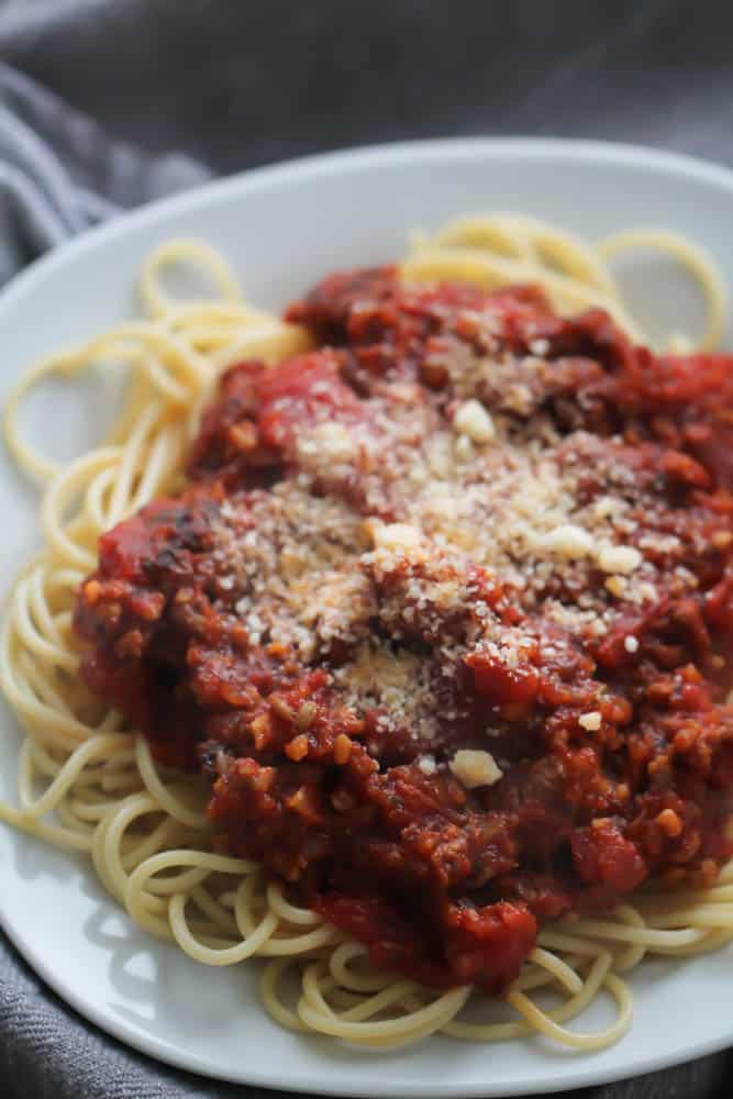 Slow Cooker Bolognese served over spaghetti on a plate