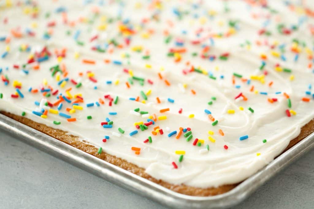 White Texas Sheet Cake frosted with sprinkles in a sheet pan.