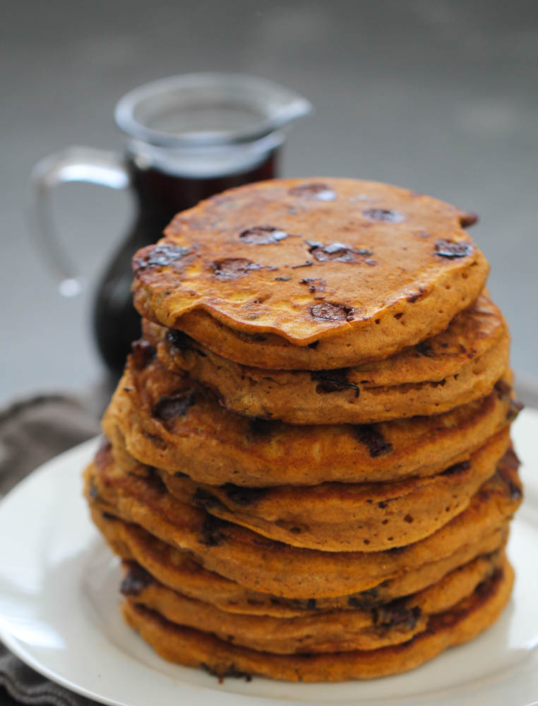 Stack of Pumpkin Chocolate Chip Pancakes with a pitcher of syrup