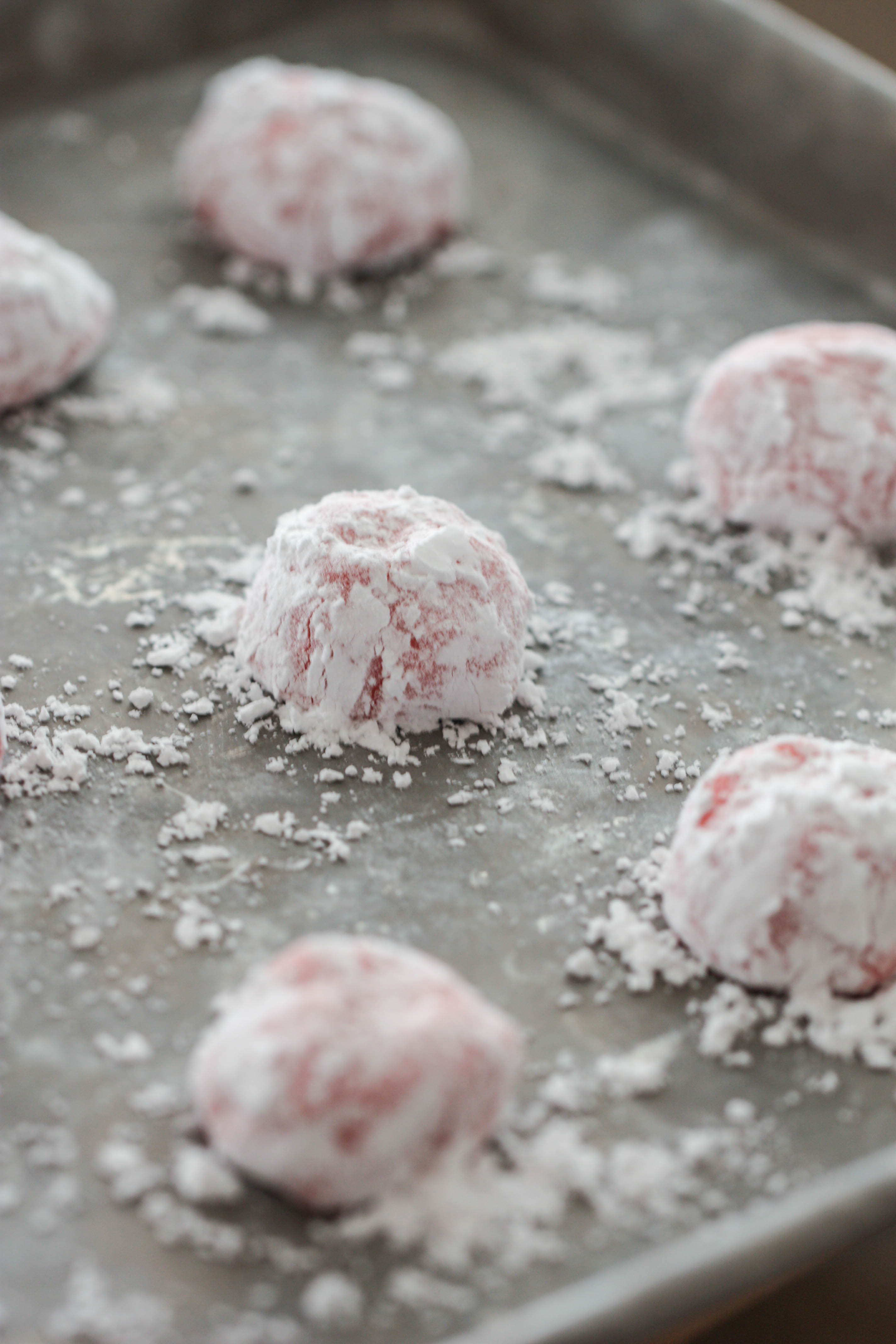 Strawberry Crinkle Cookie dough balls sprinkled with powdered sugar