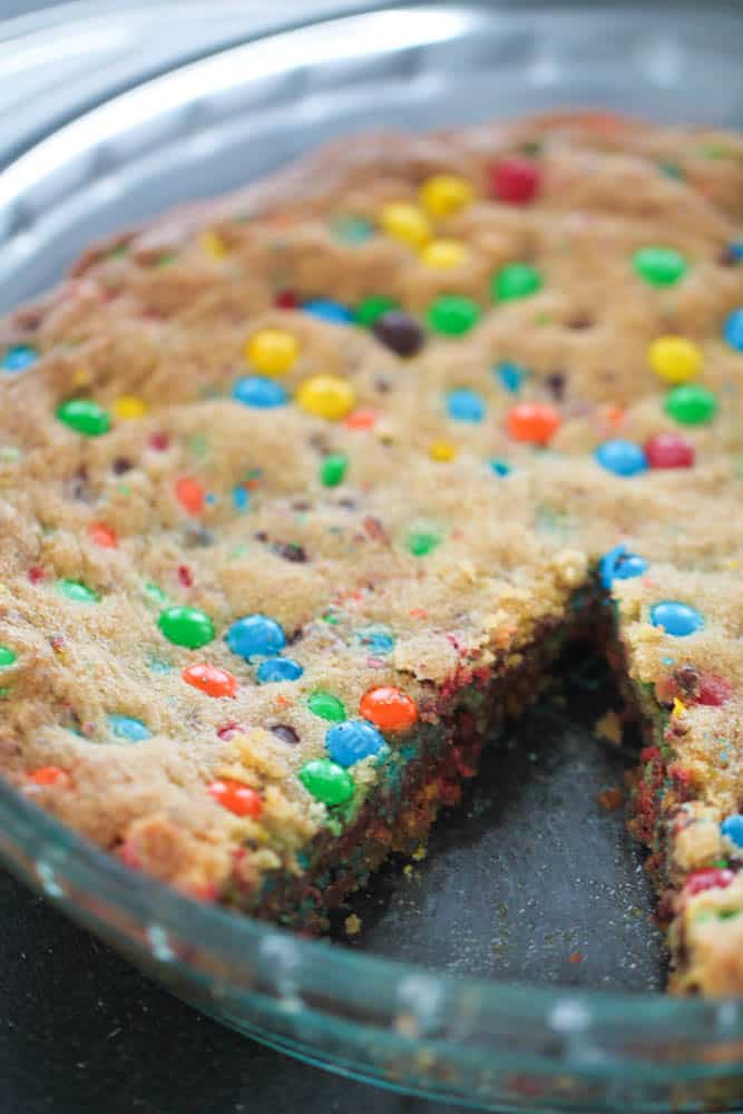 M&M Cookie Pie in glass pie dish missing one slice