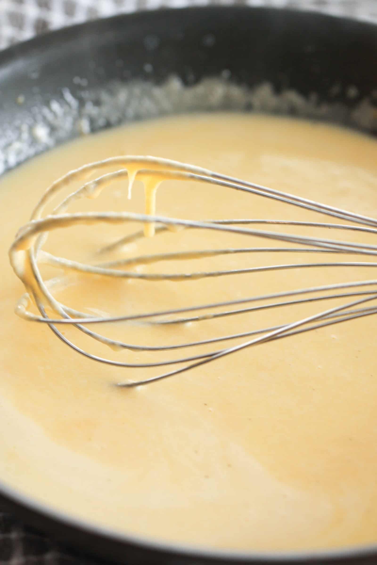 cheese sauce in a saucepan with a whisk