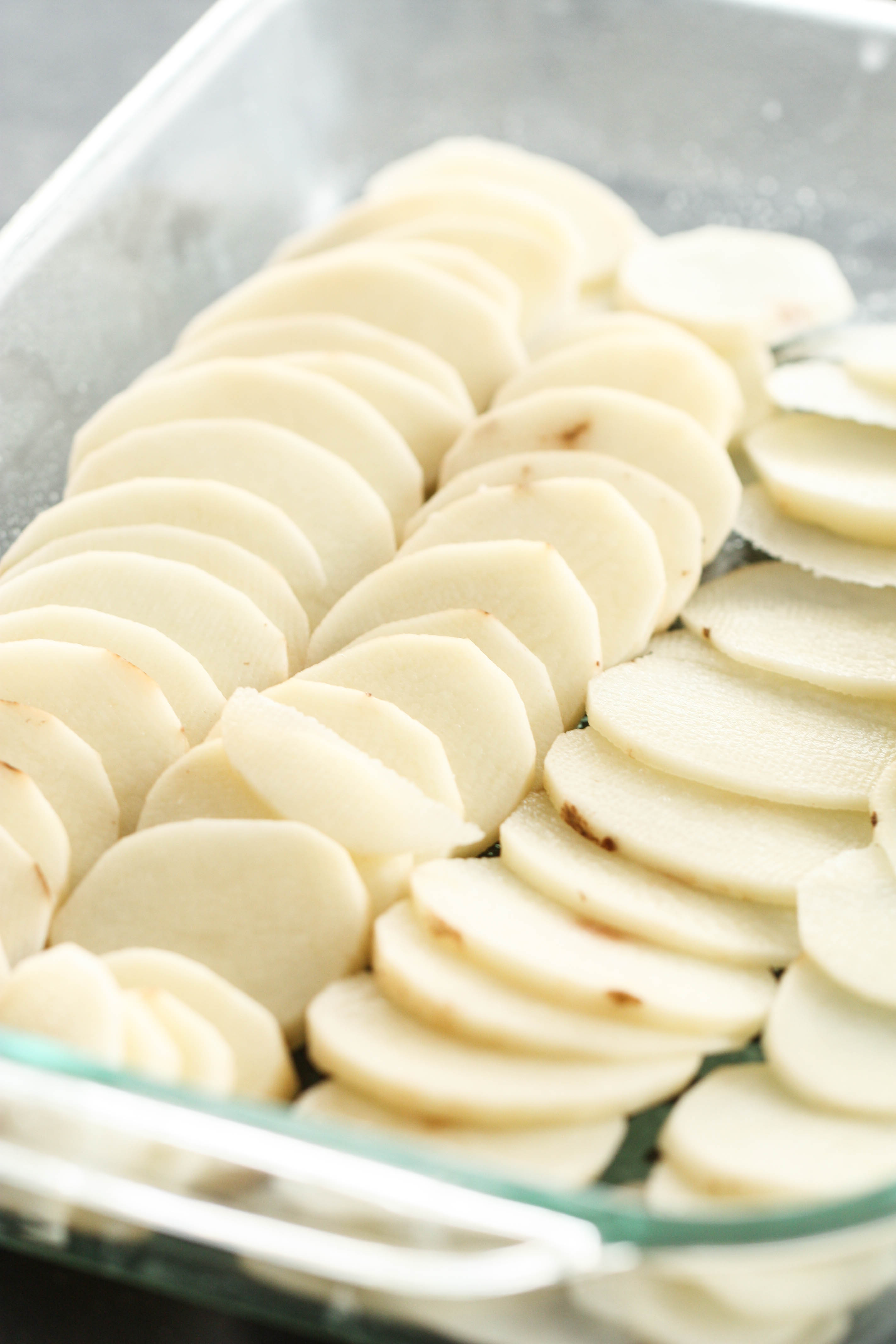 russet potatoes peeled and thinly sliced in a baking pan