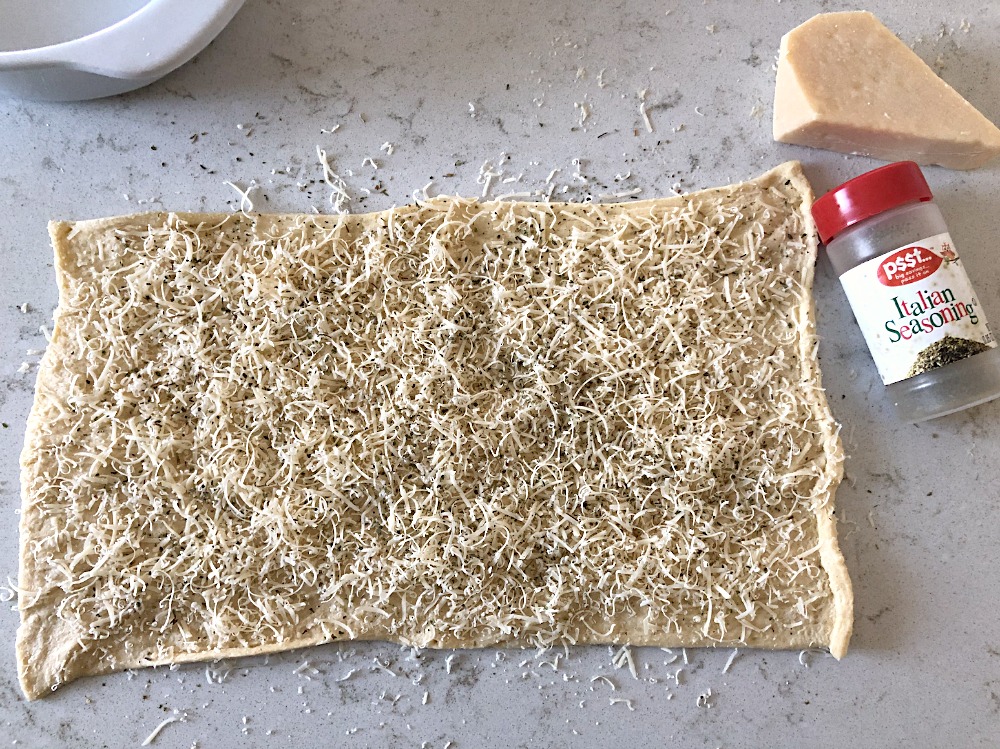 Parmesan cheese and seasoning on top of rolled out dough