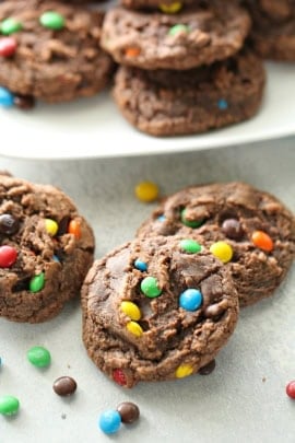 Chocolate Brownie Mix Cookies on a stand with some on the counter scattered Mini M&MS surround them.