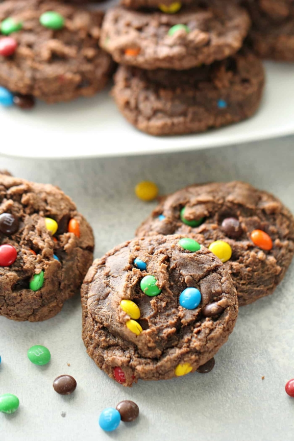 Chocolate Brownie Mix Cookies on a stand with some on the counter scattered Mini M&MS surround them.