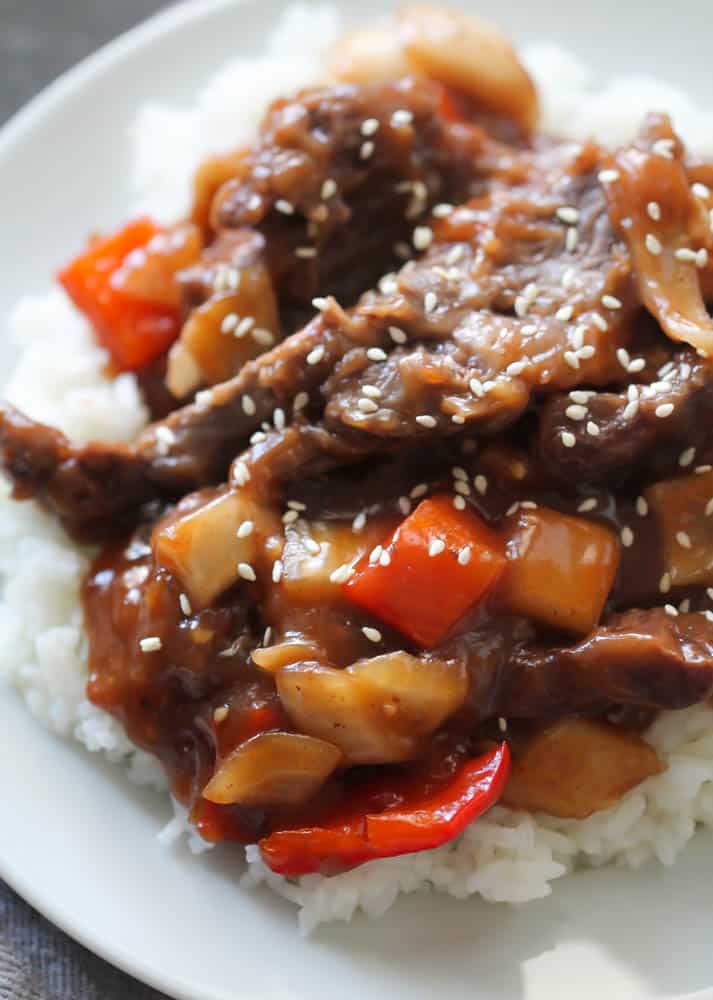 Slow Cooker Beijing Beef on top of rice on a white plate