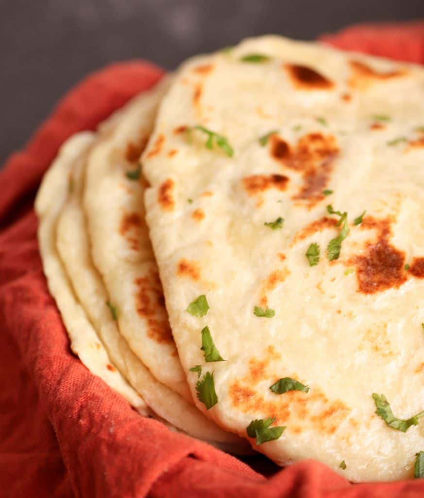 A stack of Easy Homemade Naan Bread in a red basket.