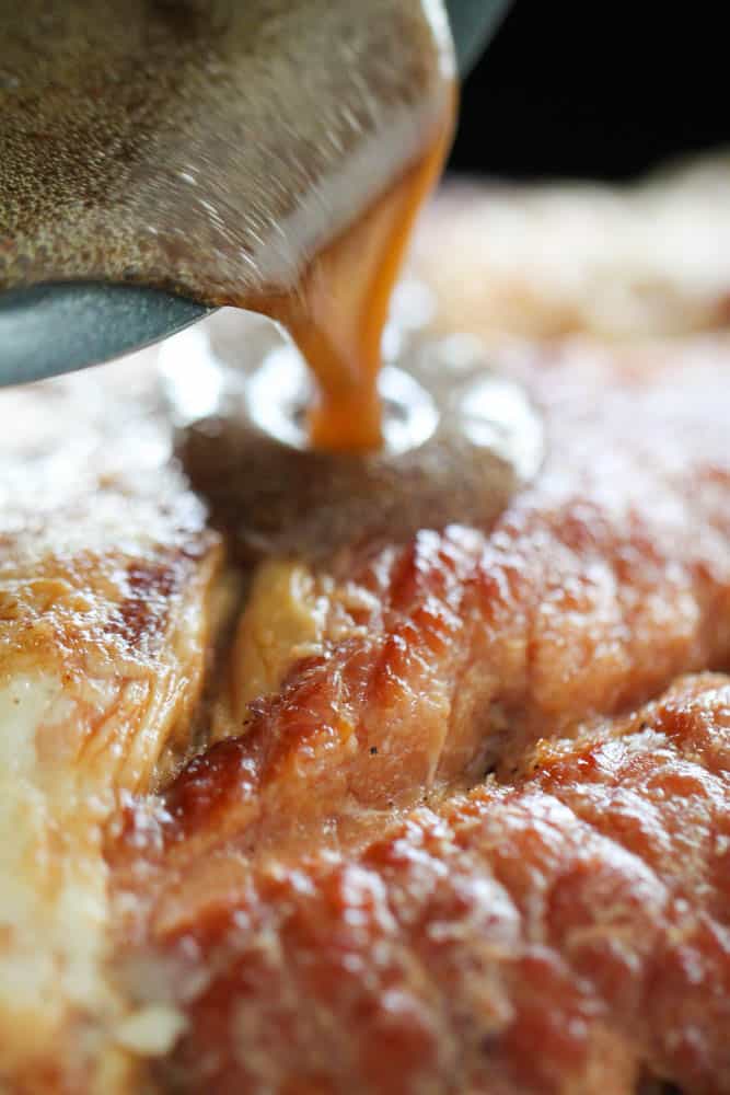 Cooked glaze being poured over ham