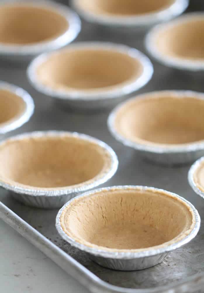Mini graham cracker pie crusts on a baking sheet.