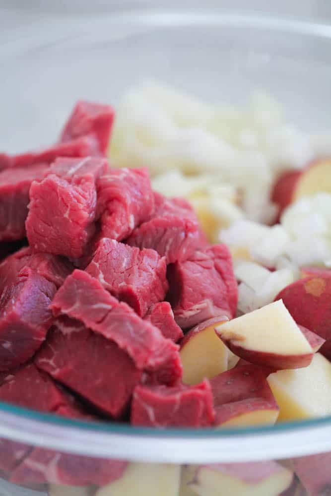 steak, potatoes and onions in a mixing bowl