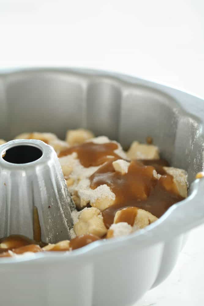 Layers of pecans, thawed rolls, pudding mixture and brown sugar and butter mixture in the bundt pan, ready to rise and then cook