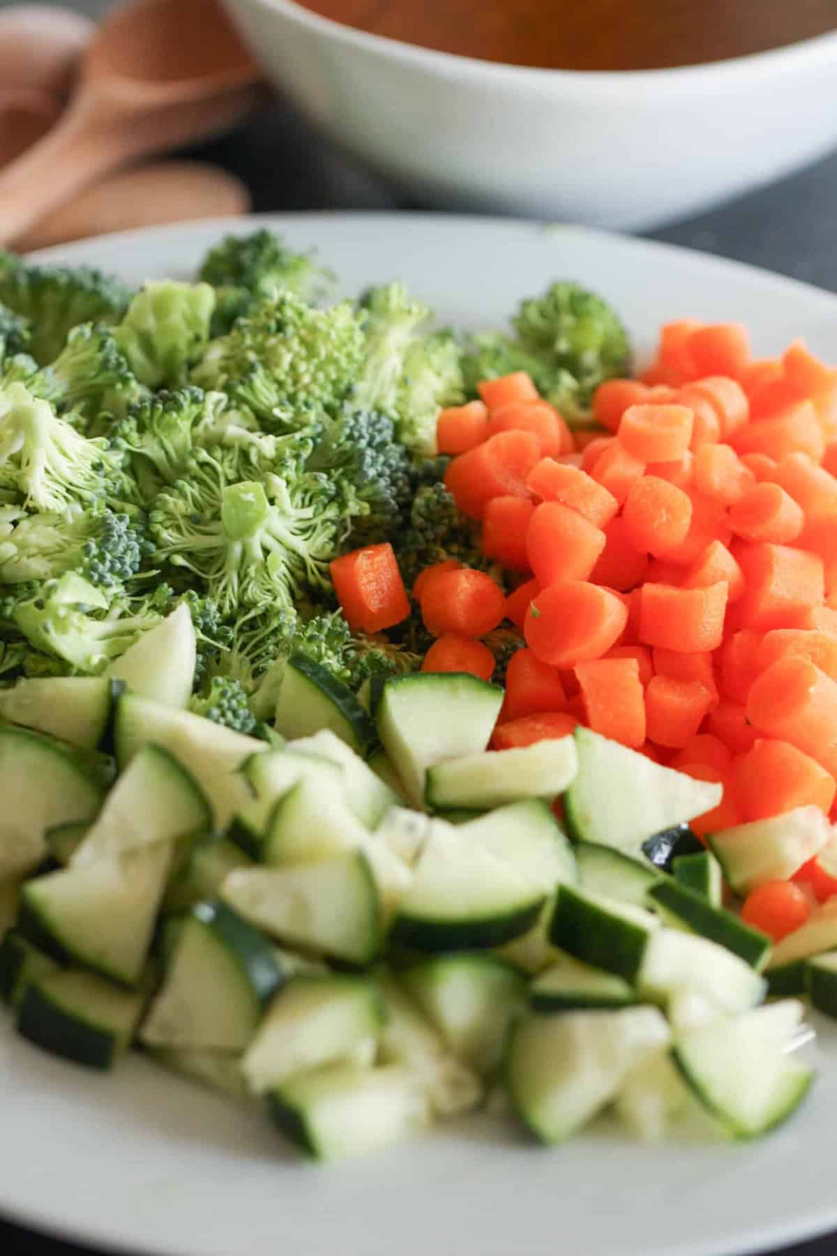 Chopped vegetables on a white plate featuring broccoli, carrots, and zucchini.