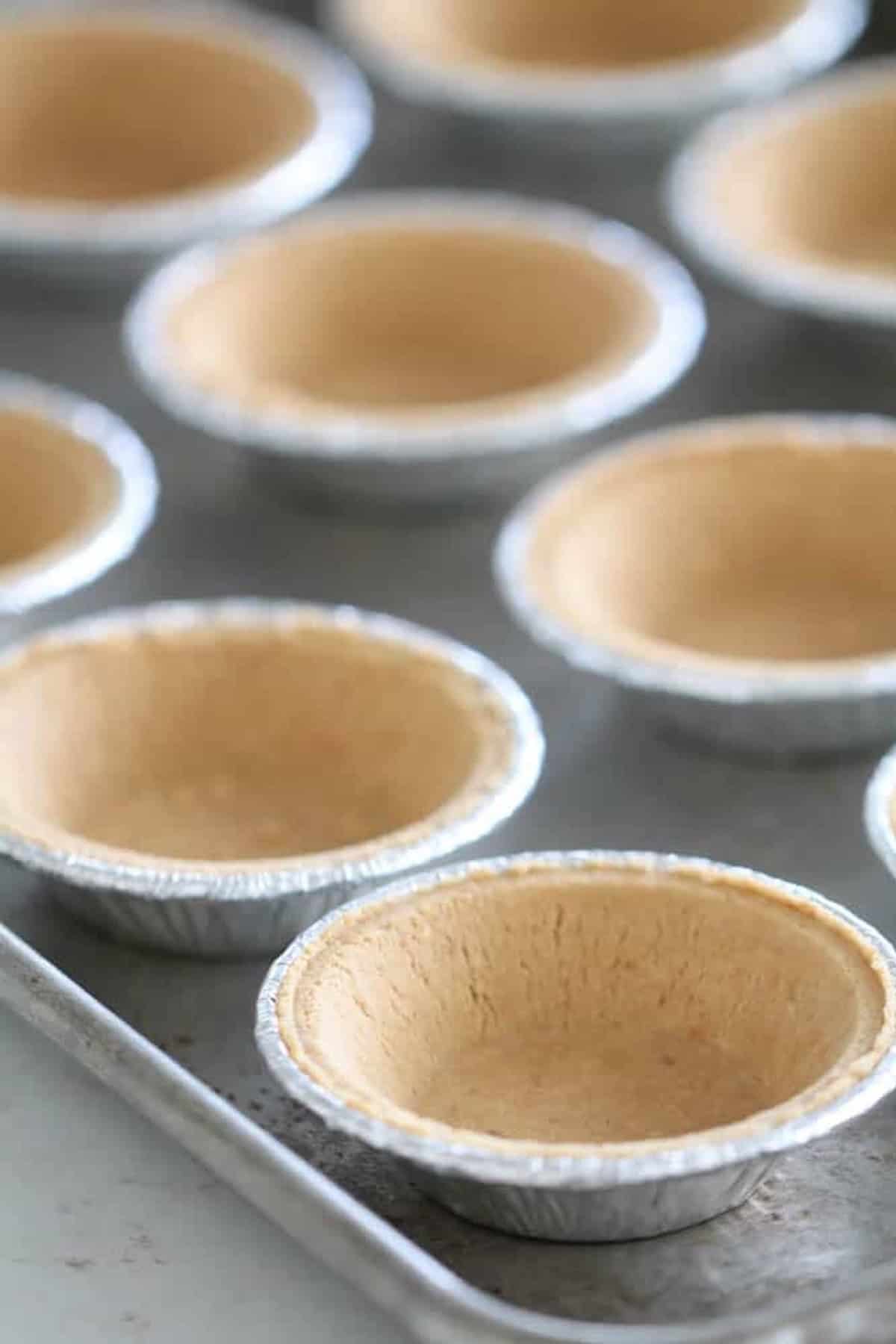Mini graham cracker pie crusts on a baking sheet.