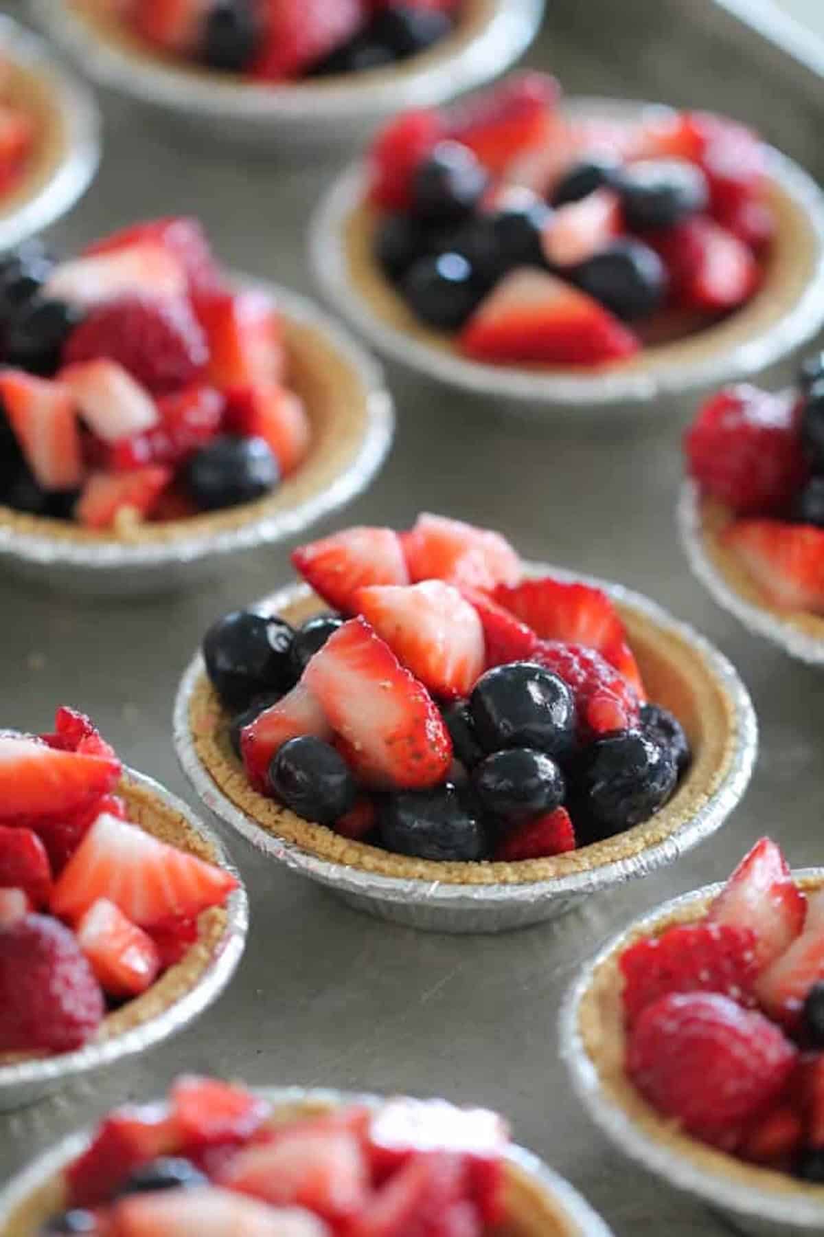 Mini pie crusts filled with berry mixture. Ready to bake on a baking sheet.