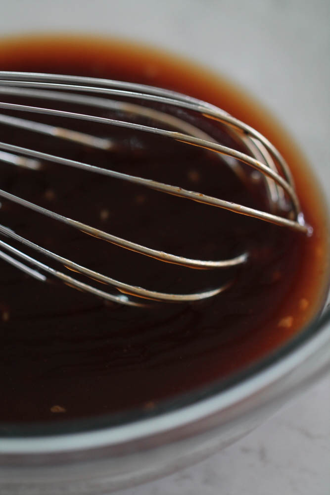 BBQ sauce mixture in a glass bowl with a whisk