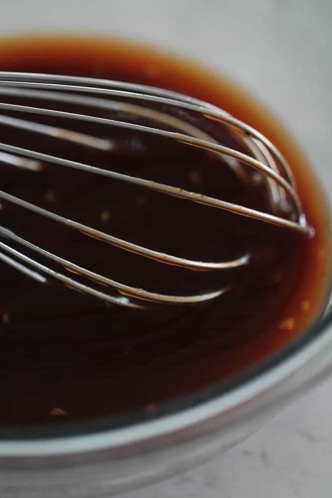 BBQ sauce mixture in a glass bowl with a whisk