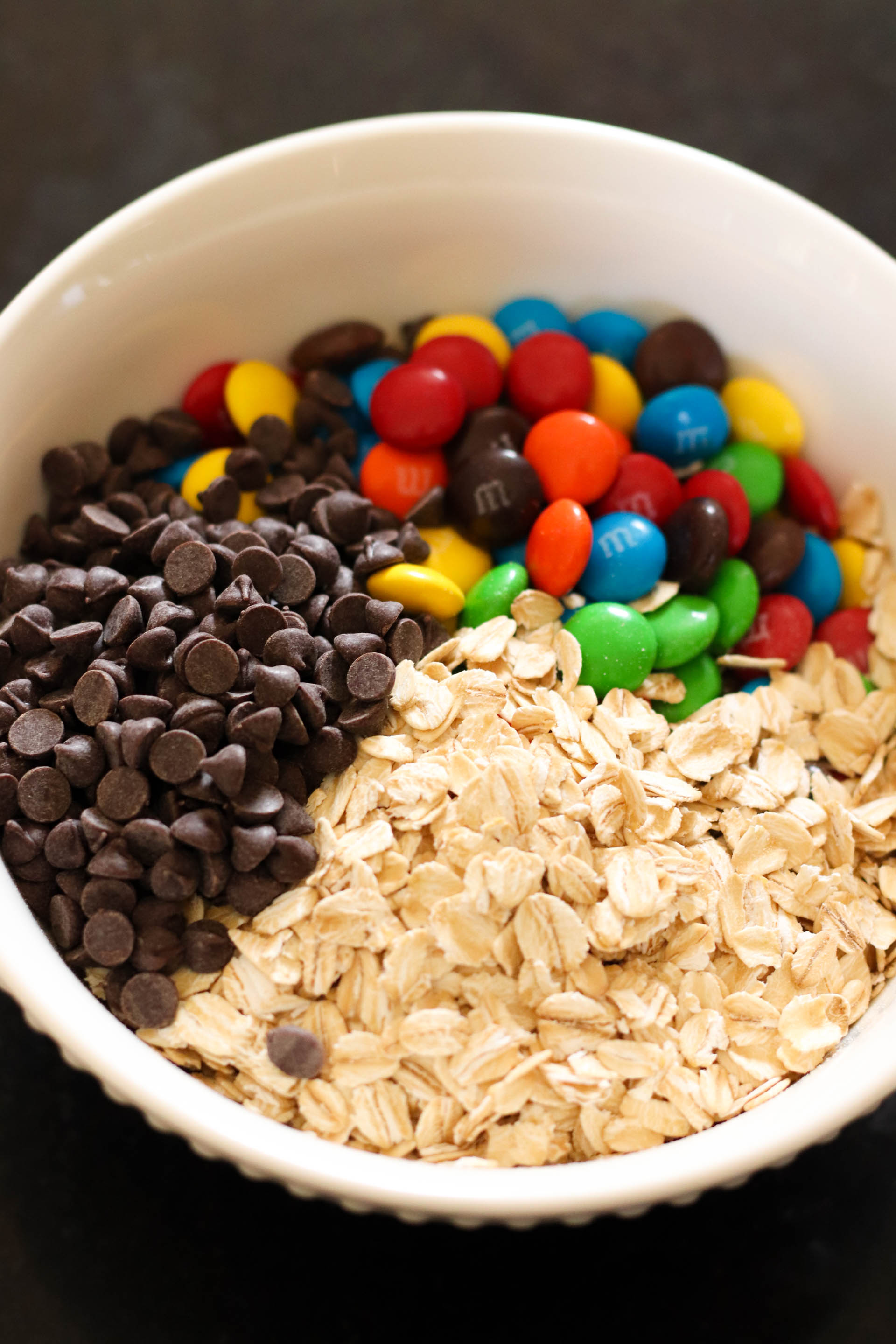 Oats, chocolate chips and M&Ms in a mixing bowl