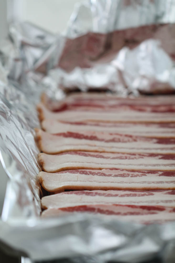 Raw bacon on a foil lined baking sheet