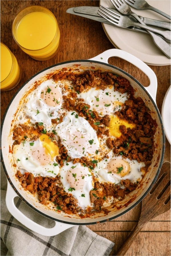 Top view of One Pan Egg and Turkey Skillet in the skillet with two glasses of orange juice on the side.