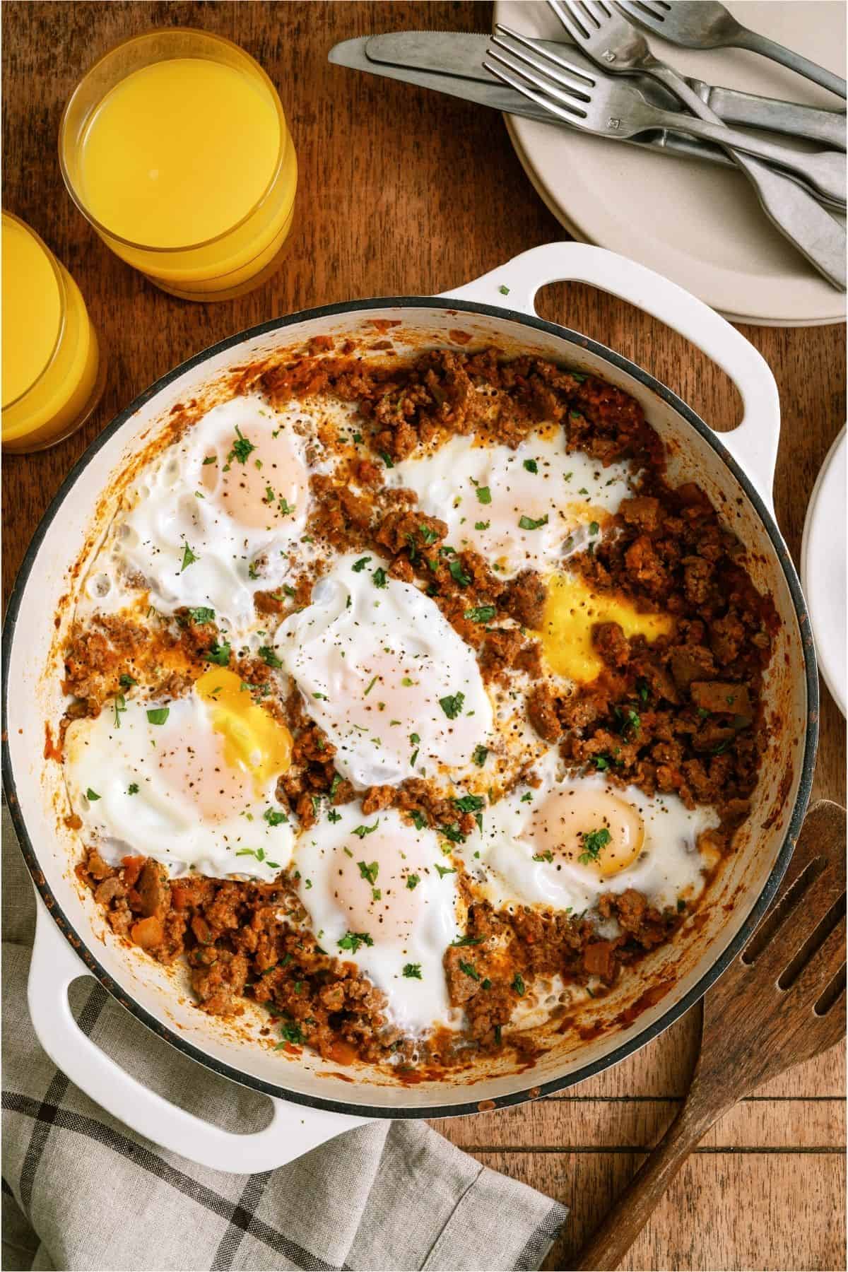 Top view of One Pan Egg and Turkey Skillet in the skillet with two glasses of orange juice on the side.