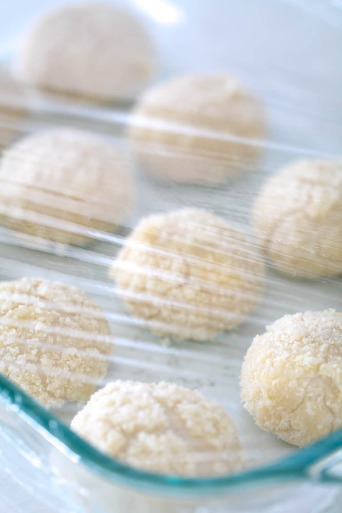 Unbaked 3 Ingredient Parmesan Rolls in a pan, covered with plastic wrap