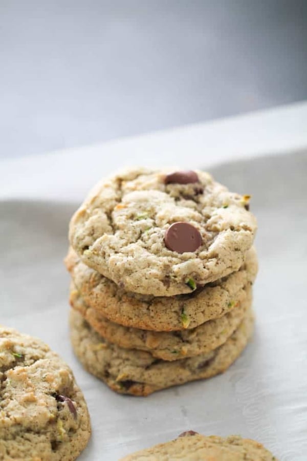 Zucchini Chocolate Chip Cookies stacked on a baking sheet lined with parchment paper.