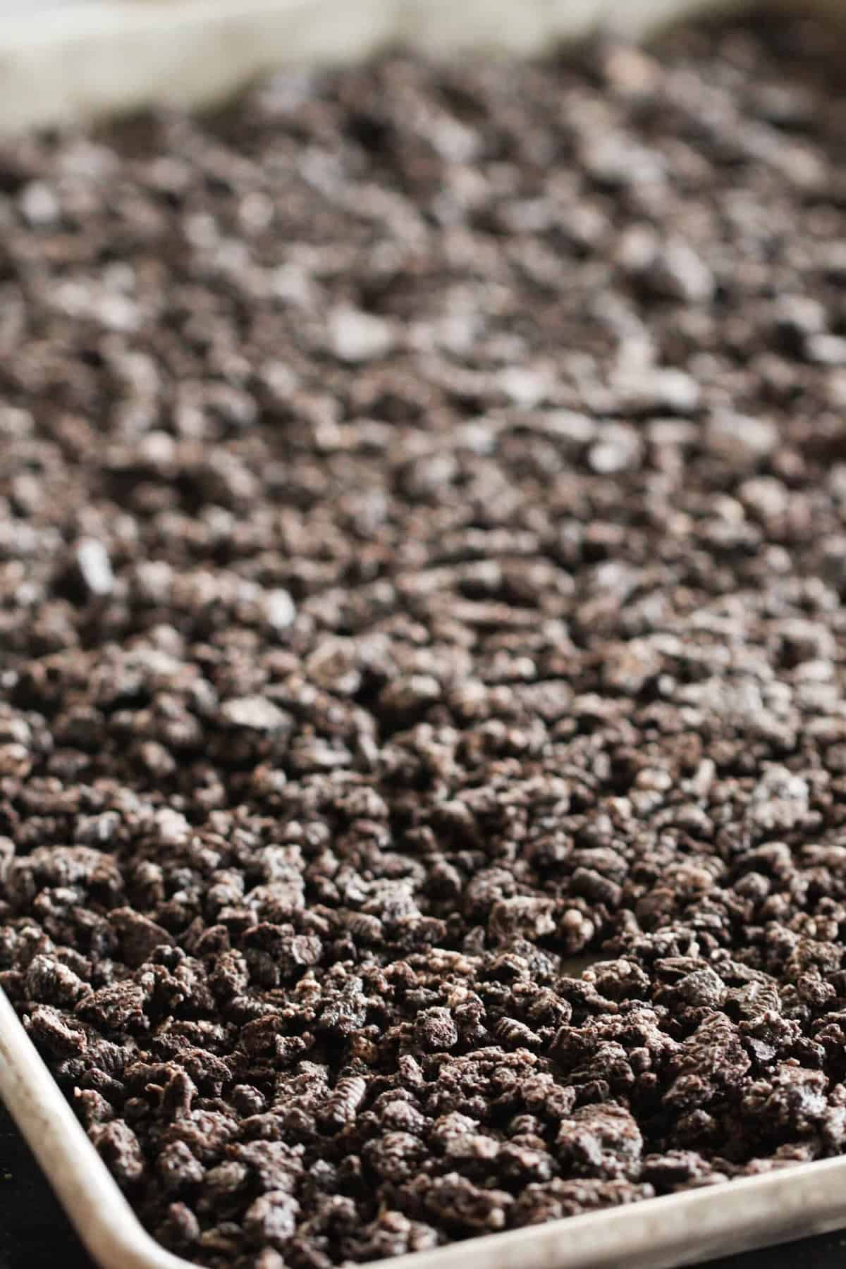 Oreo crumb mixture pressed into a baking sheet to create a crust.