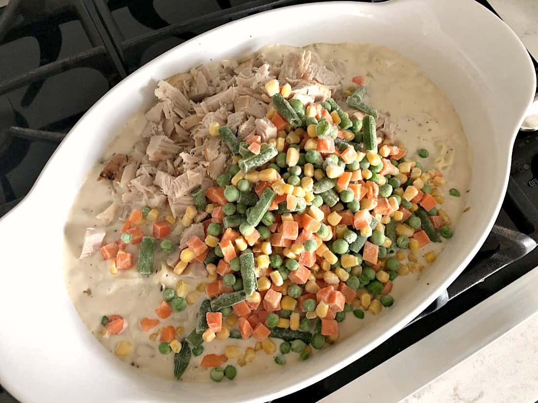 Frozen vegetables on top of chicken and sauce in casserole dish