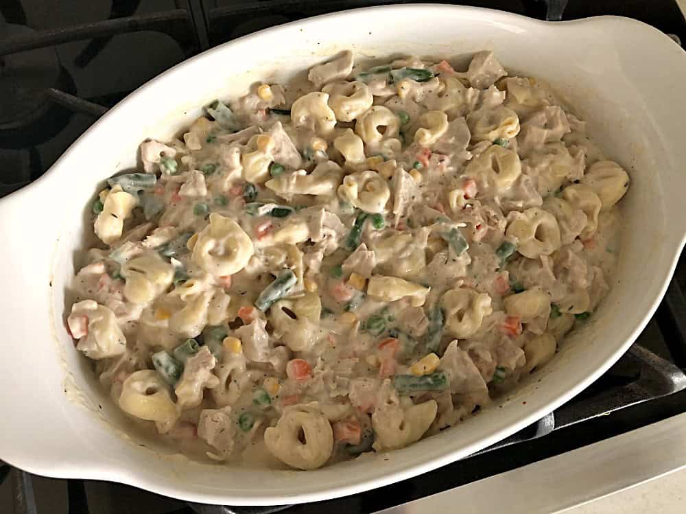 Unbaked Chicken Alfredo Tortellini Casserole in a white casserole dish