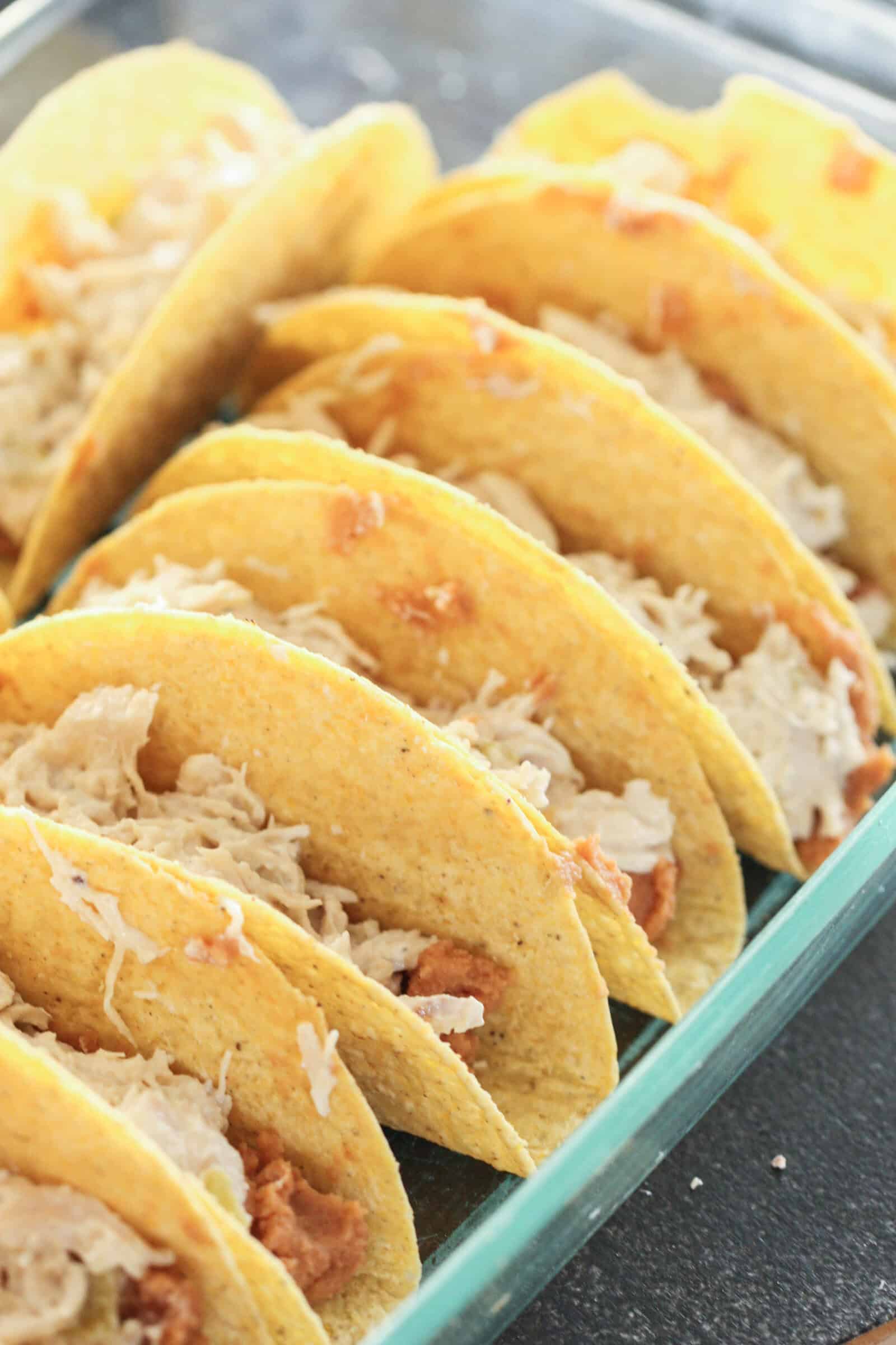 Refried beans and shredded chicken in taco shells