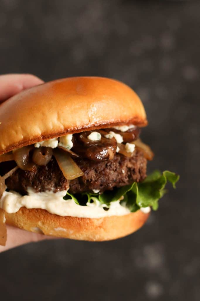 A hand holding a Black & Bleu Burger.