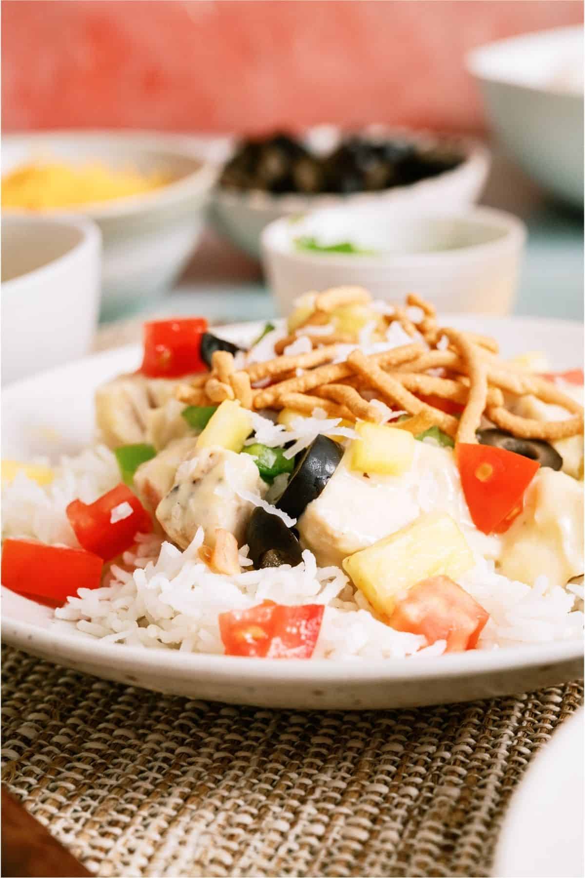 Side view of a plate with a serving of Hawaiian Haystacks and toppings.