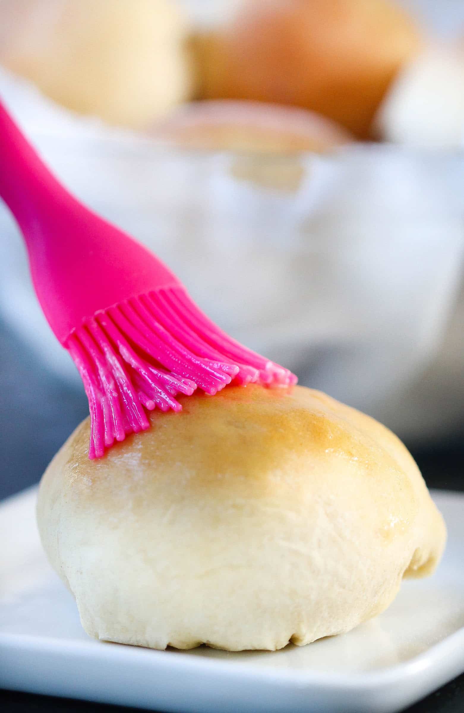 cooked roll being brushed with butter