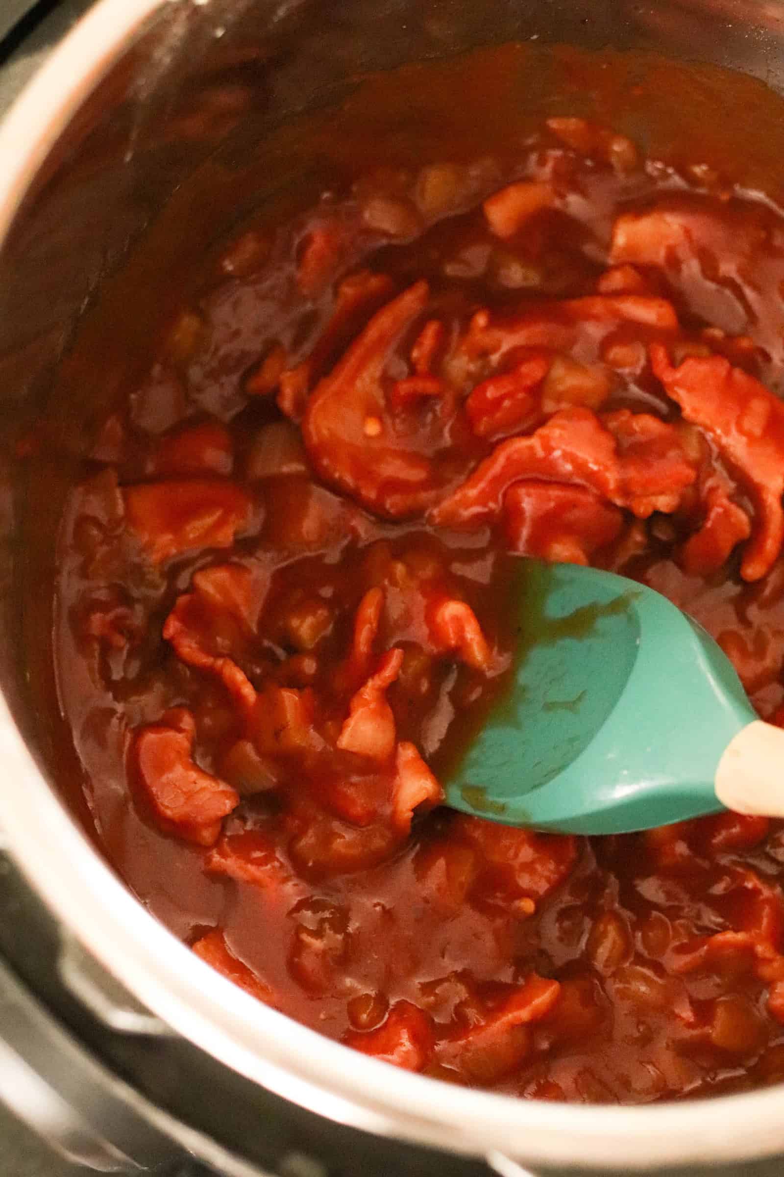 Spoon stirring Instant Pot Sweet and Spicy BBQ Beans in Instant Pot