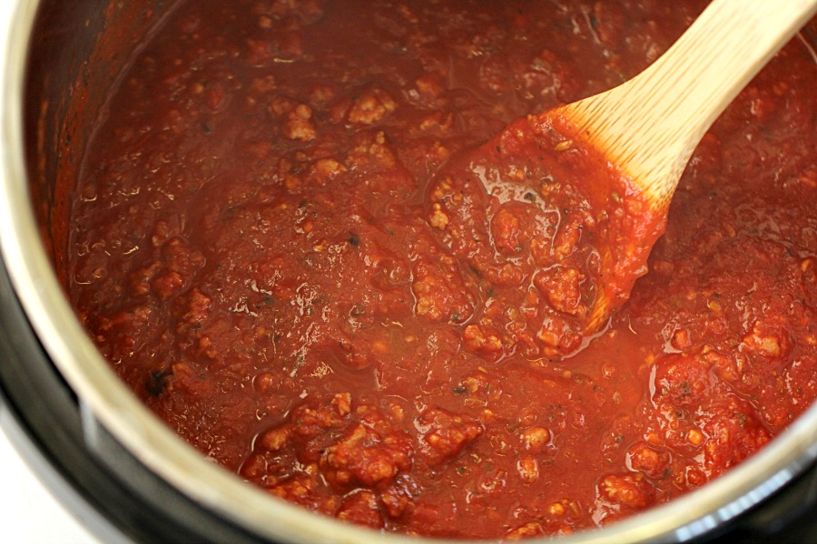 bolognese sauce being stirred with a wooden spoon in an instant pot
