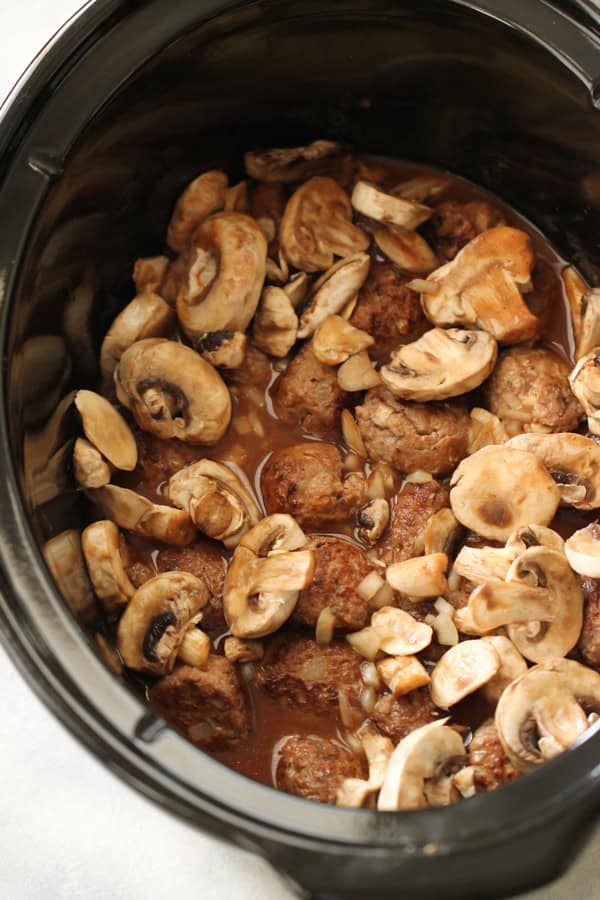 Salisbury Steak Meatballs in crockpot topped with sauce and mushrooms