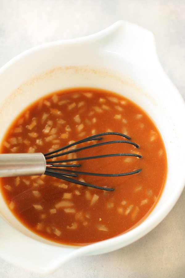 meatball sauce in a bowl with a whisk