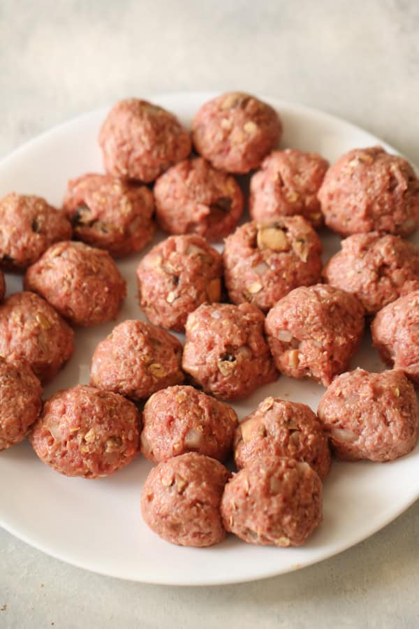 uncooked formed meatballs on white plate