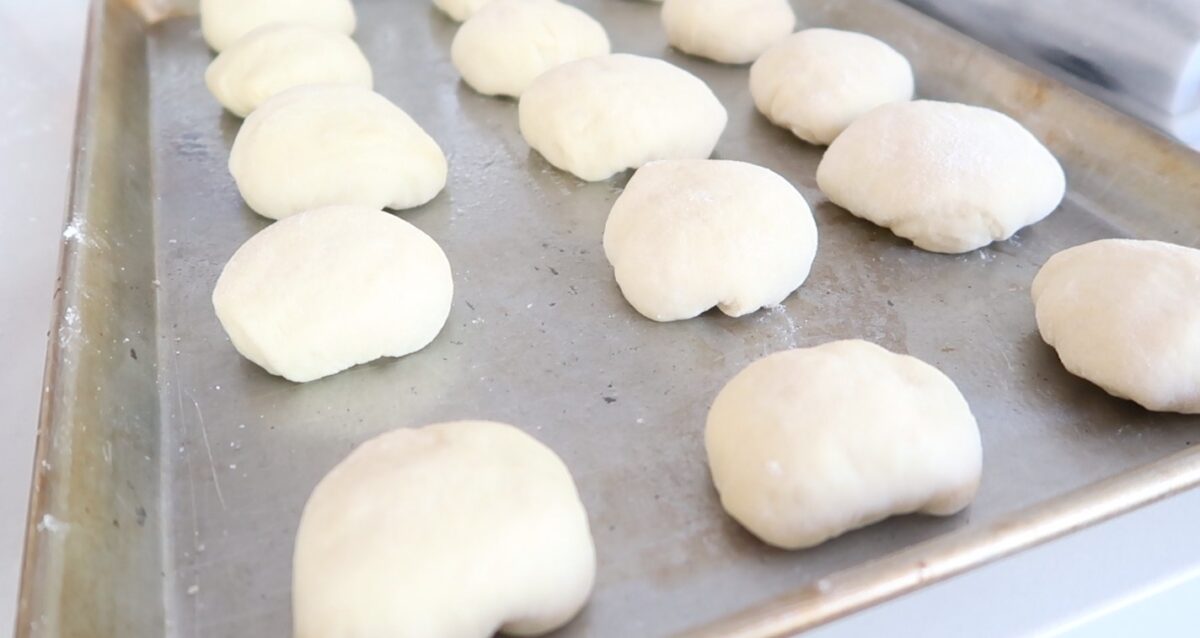 Instant Pot Rolls rising on a baking sheet.