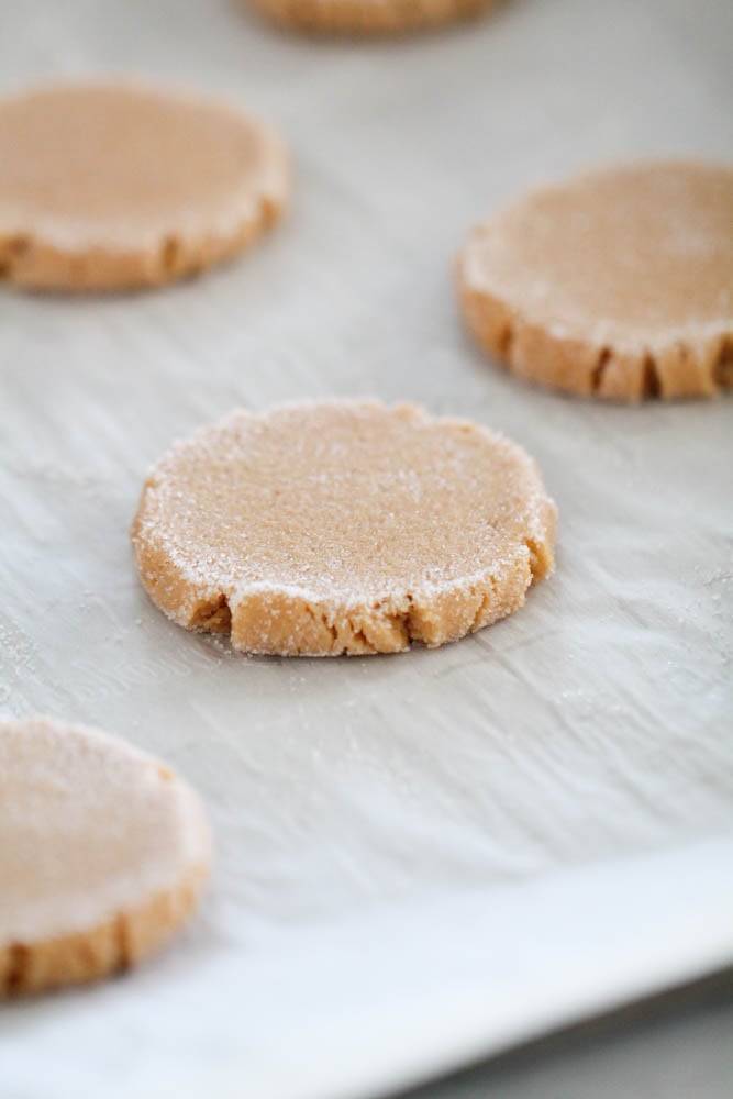 peanut butter cookies flattened with sugar on top and ready to be baked