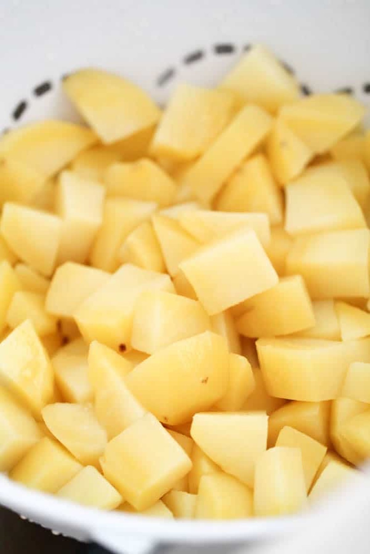 A close-up view of peeled and chopped potatoes in a bowl, ready for cooking or further preparation.