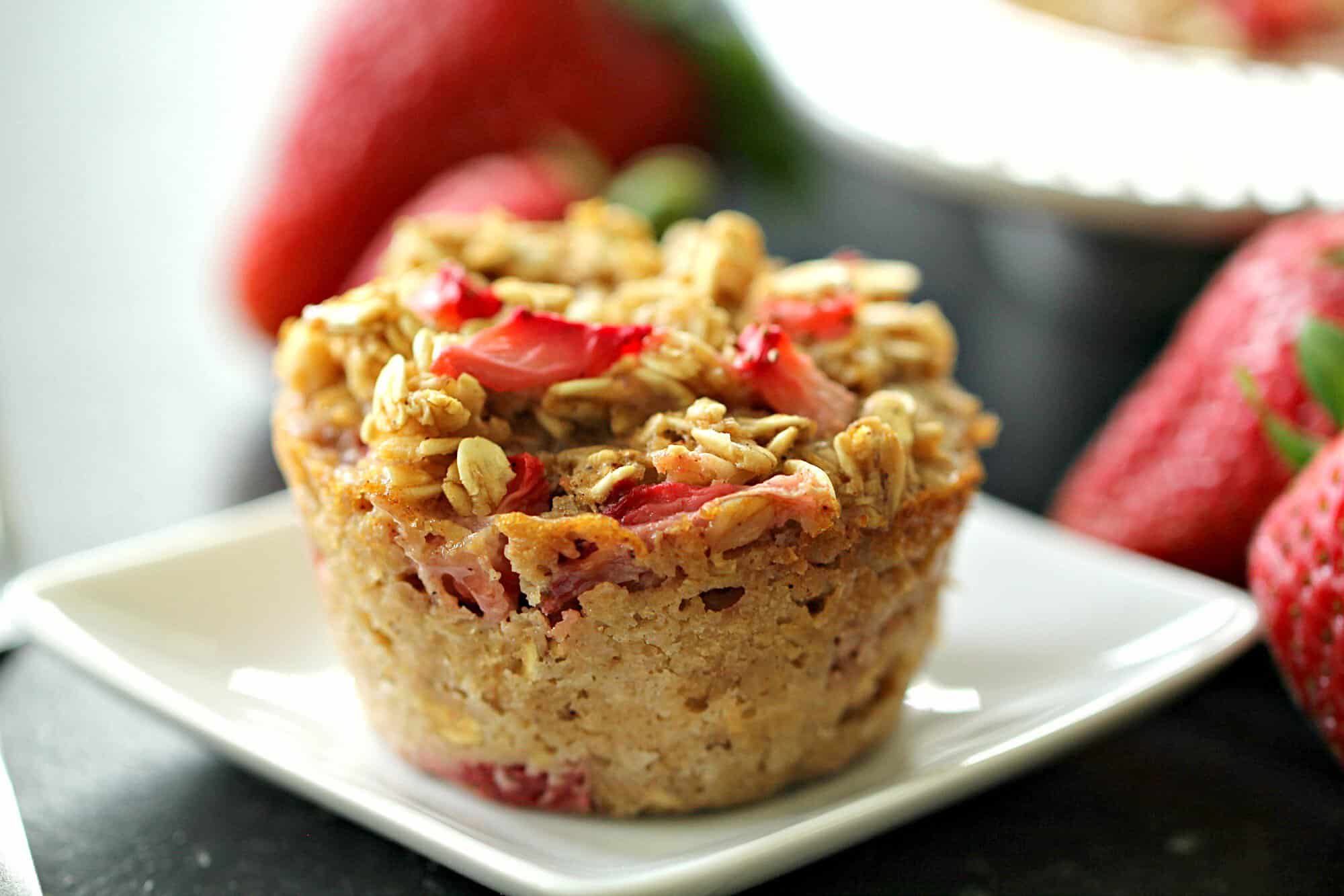 single baked oatmeal muffin cup topped with strawberries on a white plate