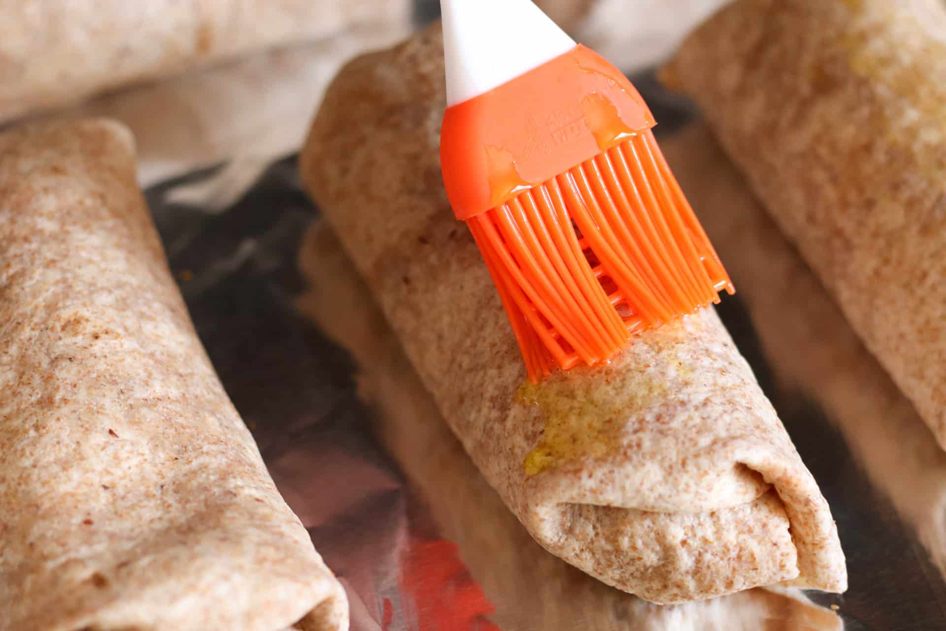 Brushing tops of Bean and Rice Burritos