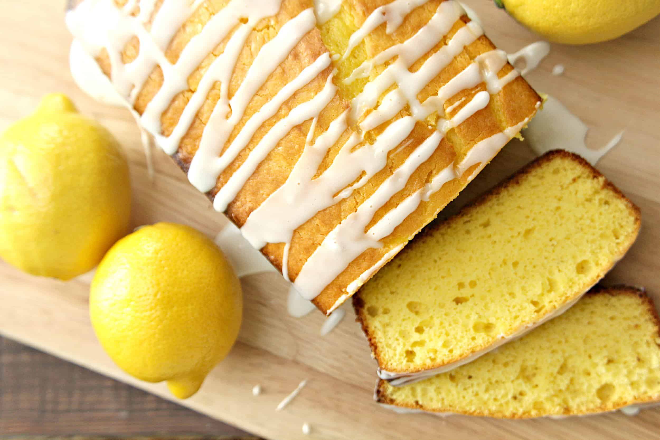 Starbucks Copycat Lemon Pound Cake sliced on a cutting board with lemons